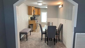 A compact kitchen with wooden cabinets, a dining table with four chairs, and a bench. - Nature & Comfort: Charming 3BR Palmetto-Ellenton Home, Sleeps 6, WiFi & AC (Palmetto)