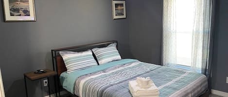 A bedroom with a bed, a nightstand, a ceiling fan, and two framed pictures on the wall.