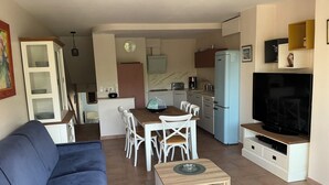 A compact living space with a sofa, dining table, chairs, a TV, and a kitchenette. - Appartement Le Lavandou centre (Le Lavandou)
