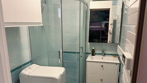 A bathroom with a glass shower enclosure, a white sink, and a mirror above the sink. - Appartement Le Lavandou centre (Le Lavandou)