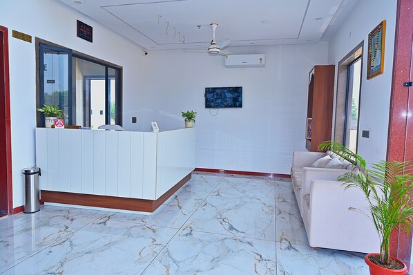 A reception area with a reception desk, a sofa, and potted plants.