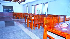 A spacious room with multiple wooden tables and chairs arranged for dining. - HOTEL MADHUVAN & RESORT (Danta Ramgarh)
