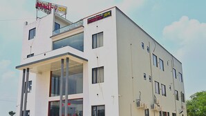 A modern building with a flat roof, multiple windows, and a signboard at the top. - HOTEL MADHUVAN & RESORT (Danta Ramgarh)