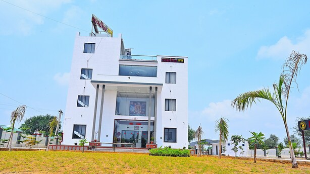 A modern building with a large entrance, multiple windows, and a sign above the entrance. - HOTEL MADHUVAN & RESORT (Danta Ramgarh)