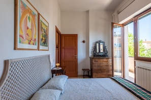 A bedroom with a bed, wooden dresser, and artwork on the wall.