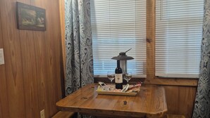 A wooden interior with a table set for two, a bench, and a window with blinds.
