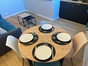 A dining area with a round wooden table set for four, each place setting with a white plate, a wine glass, and cutlery. - Duplex apartment in Honfleur town center, a few minutes from the old port (Honfleur)