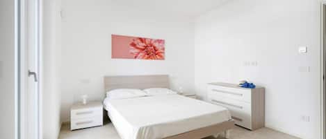 A bedroom with a bed, nightstands, a dresser, and a wall-mounted flower painting.