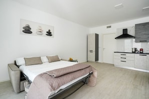 A modern bedroom with a bed, bedside table, and a painting of stones.