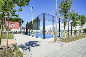 A modern building with a glass facade, surrounded by trees and a paved walkway.