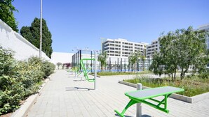 A paved walkway with exercise equipment, a green table, and a white building in the background. - GuestHost - Charming 67 sqm apartment, perfect for 4 people, located on the ground floor of a recently built building.The property is located in a residence with a concierge active all day; outside the house there are gym equipment that can be used freel (Bari)