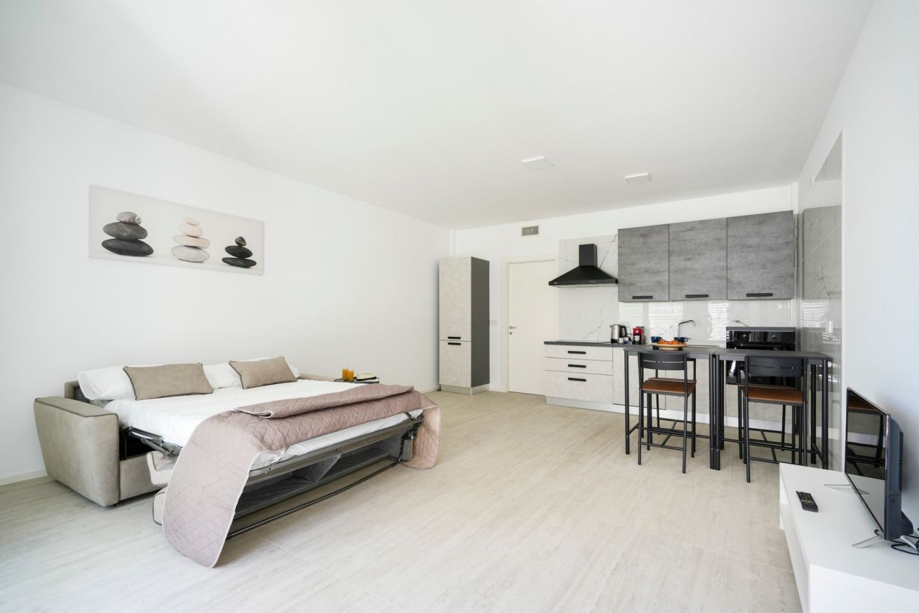Ein modernes, kompaktes Wohnzimmer mit Schlafsofa, einer Küchenzeile und einem Essbereich.