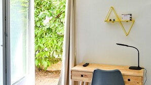 Una habitación con una cama, un escritorio con una silla, una lámpara y una ventana con cortinas.