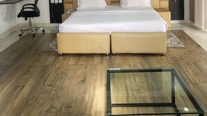 Ein modernes Schlafzimmer mit einem großen Bett, einem Glastisch, einem Schreibtisch und einem Stuhl.
