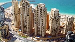A high-rise residential building complex with multiple towers, a central courtyard, and a beach in the background. - Tratoli Hostel in JBR with Sea Views (Dubai)
