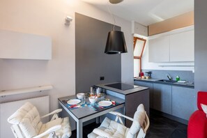 Une cuisine moderne avec un îlot central, un coin repas comprenant une table et des chaises, et une chaise rouge.