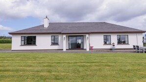 A single-story building with a flat roof, a front door, and a small porch area. - ARD NA MARA, pet friendly, with open fire in Culdaff, County Donegal (Culdaff)