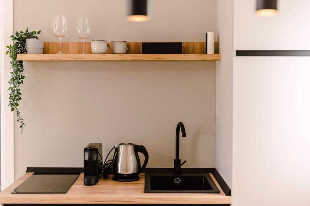 Cozinha compacta com bancada de madeira, pia embutida, chaleira e cafeteira.