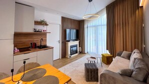 Un saló modern amb un sofà, un pouf i una zona de menjador amb una taula de fusta i cadires.
