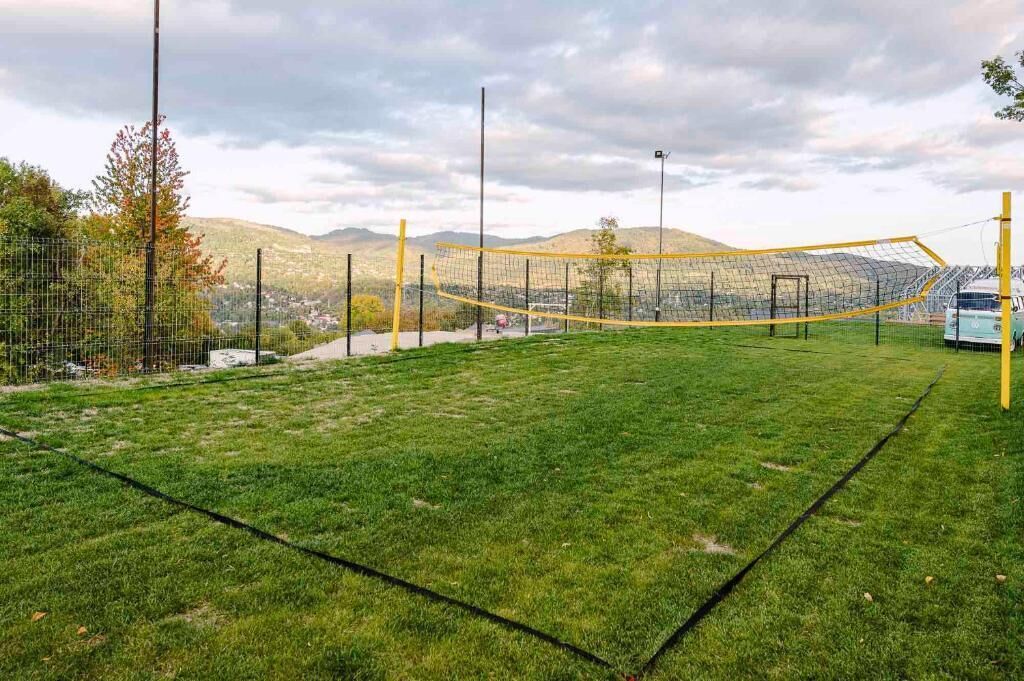 A sports field with a netted goal area, surrounded by a fence and trees.