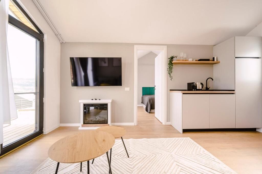 A modern kitchen with white cabinets, a built-in oven, and a flat-screen TV mounted above the counter.