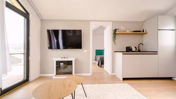 A modern kitchen with white cabinets, a built-in oven, and a flat-screen TV mounted above the counter.