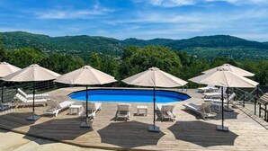 Zona de piscina amb gandules i ombrelles, amb vista a un paisatge montanyós.