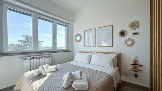 A bedroom with a large bed, a window, and wall decorations.