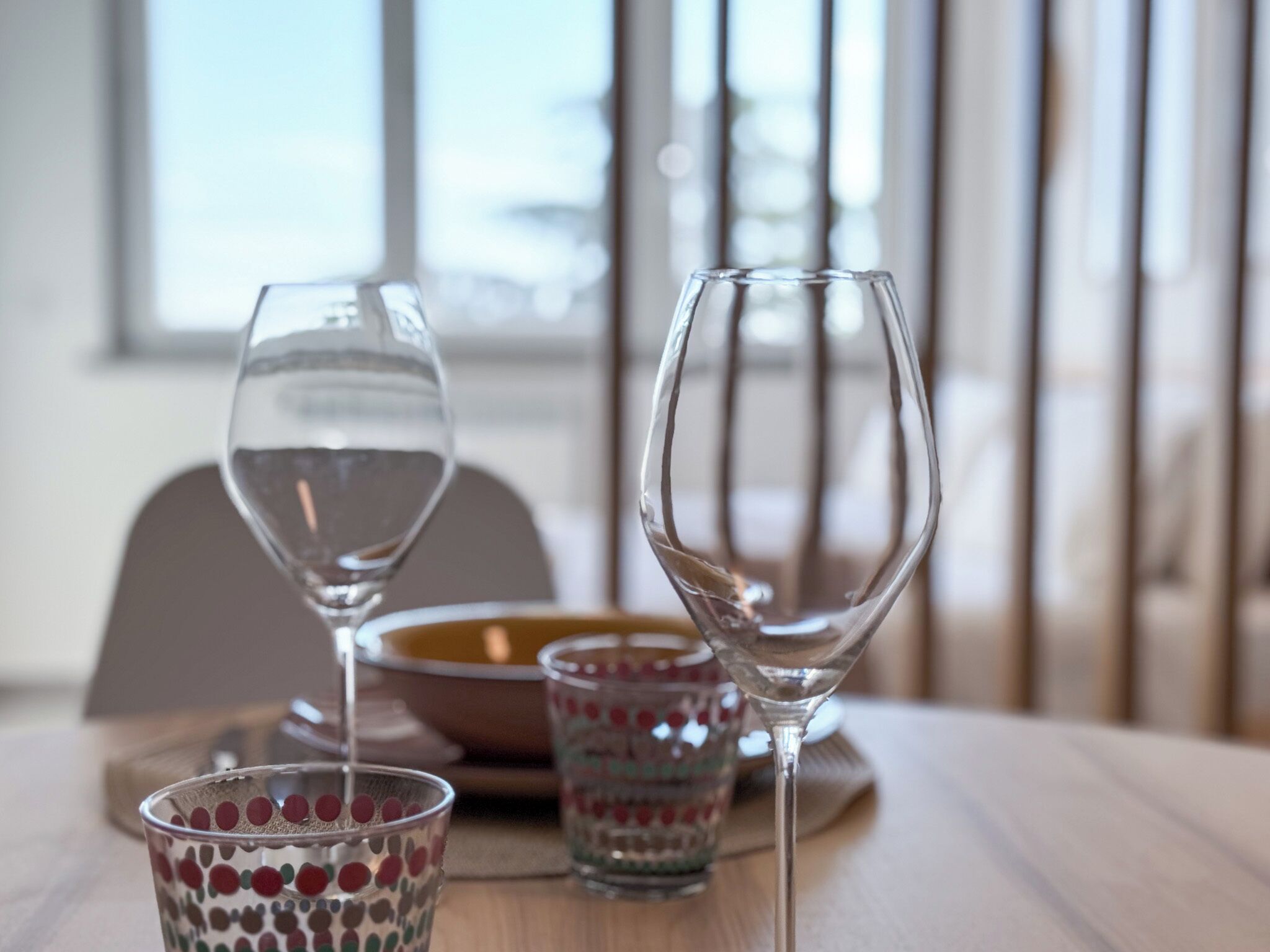 Ein Esstisch mit zwei Weingläsern und einem Glas mit Muster.