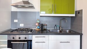A modern kitchen with a gas stove, oven, stainless steel sink, and green cabinets.
