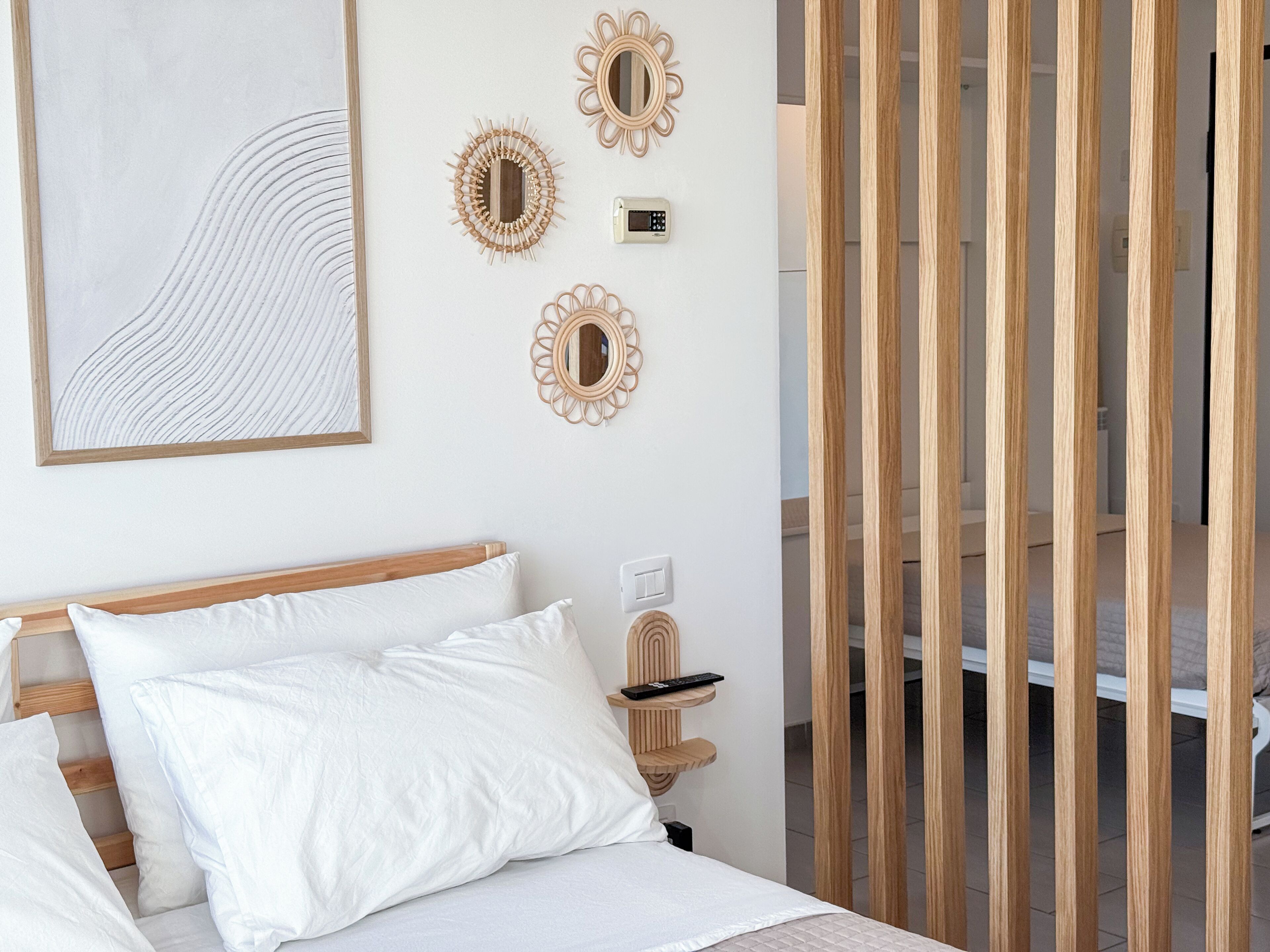 Ein Schlafzimmer mit einem Bett, Kissen, einem Nachttisch mit Fernbedienung und Wanddekoration.