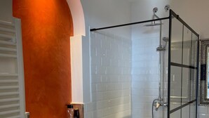 A modern bathroom with white subway tiles, a glass shower enclosure, and a towel rack.