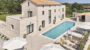 A modern building with a swimming pool, stone exterior, and outdoor seating area. - Villa Madora in Porec (Porec)