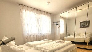 A hotel room with a bed, a mirror, and a window with curtains. - Apartment in Winterberg Near Ski Lift (Winterberg)
