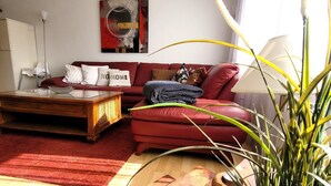 A living room with a red sofa, a wooden coffee table, and a potted plant. - Apartment in Winterberg Near Ski Lift (Winterberg)