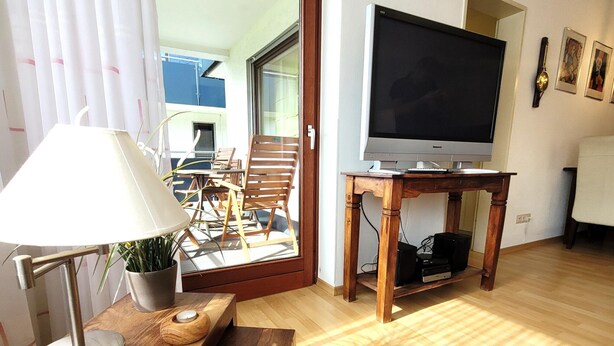 A living room with a wooden table, a lamp, a TV, and a potted plant. - Apartment in Winterberg Near Ski Lift (Winterberg)