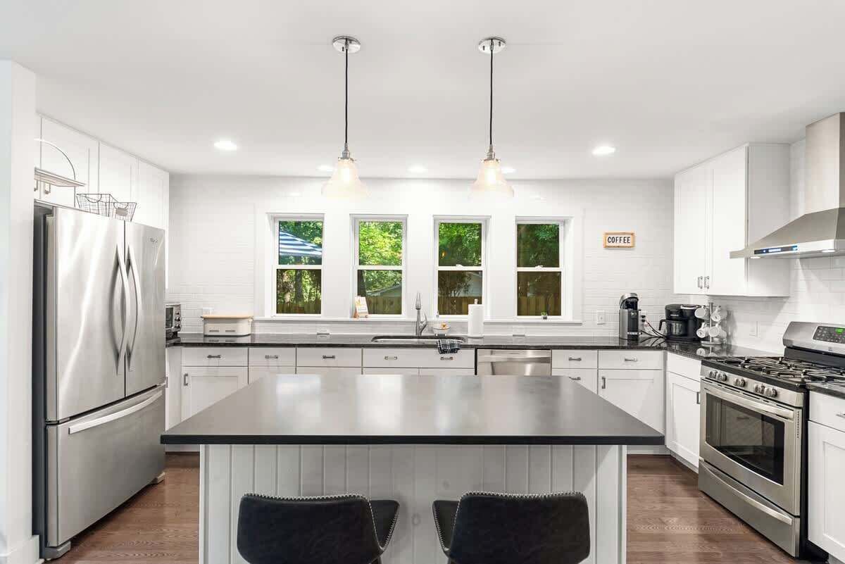 A modern kitchen with a large island, stainless steel appliances, and pendant lighting.