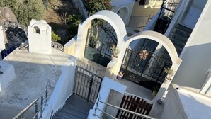 A staircase with metal railings leading to a gated entrance. - New Villa Sostis (Santorini)