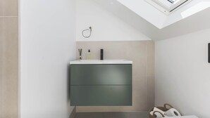 A modern bathroom with a skylight, a built-in sink, and a towel rack. - High-End 2BR/2BA with Private Outdoor Space (Greater London)