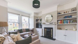 A living room with a fireplace, bookshelves, and a television. - High-End 2BR/2BA with Private Outdoor Space (Greater London)
