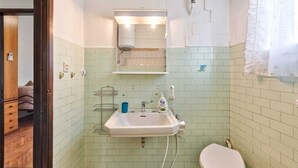 A bathroom with a sink, toilet, and a mirror above the sink. There is a window with a curtain, and the walls are tiled. - Cozy Miranese Venice (Chirignago-Zelarino)