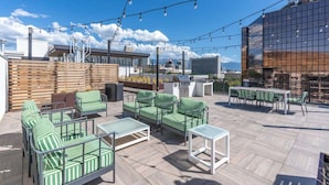 A rooftop patio with outdoor seating, a grill, and a view of the cityscape.