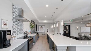 A modern kitchen with a large island, stainless steel appliances, and pendant lighting.