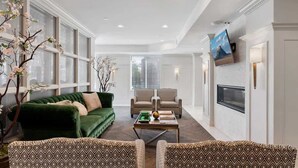 A living room with a green sofa, patterned armchairs, a coffee table, and a fireplace.