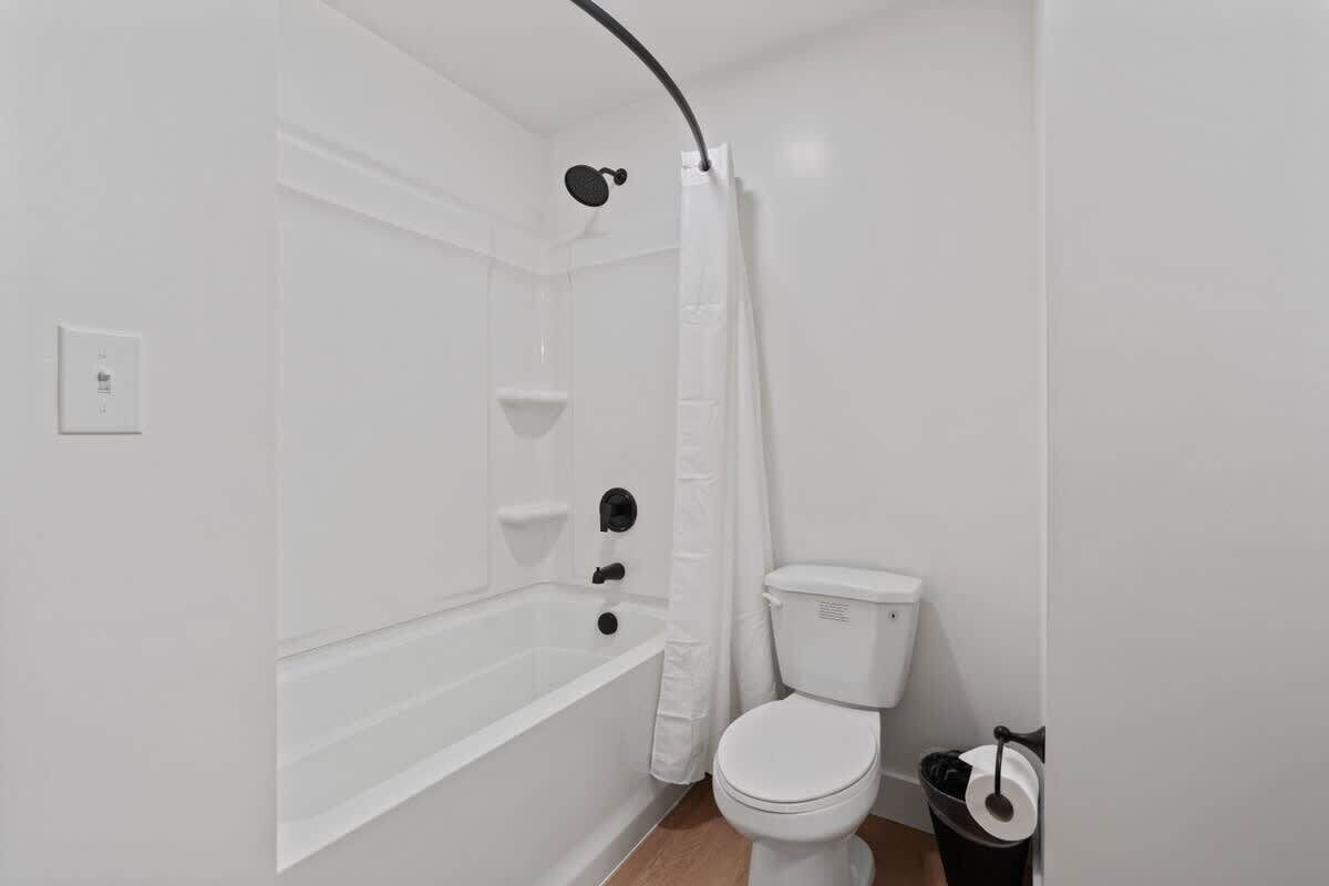 A bathroom with a bathtub, toilet, and shower curtain.