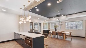 A modern kitchen with a central island, wooden flooring, and pendant lighting.