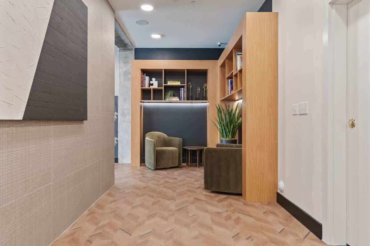 Un intérieur moderne avec un parquet en chevrons, une bibliothèque en bois, un canapé et une plante en pot.