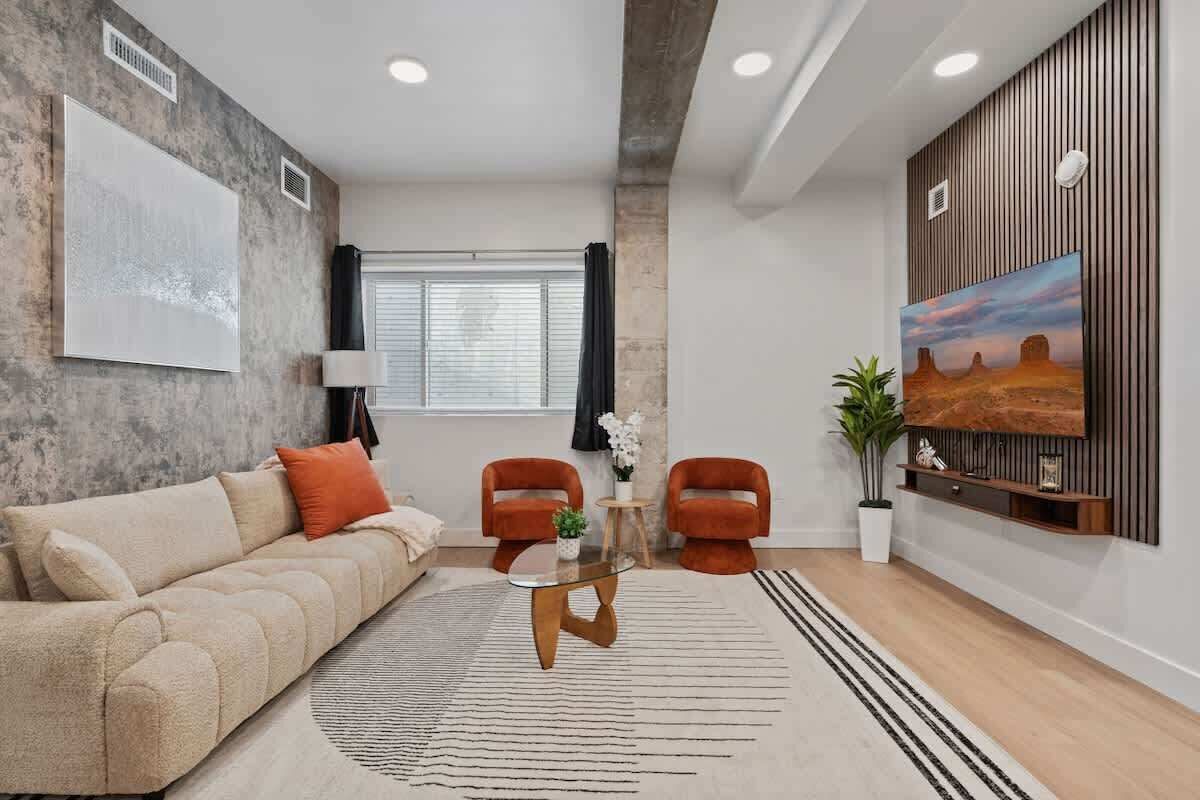 A modern living room with a sofa, two armchairs, a coffee table, and a painting on the wall.