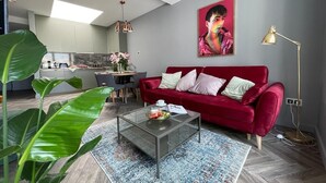 Ein modernes Wohnzimmer mit einem roten Sofa, einem Glastisch und einer großen Pflanze.