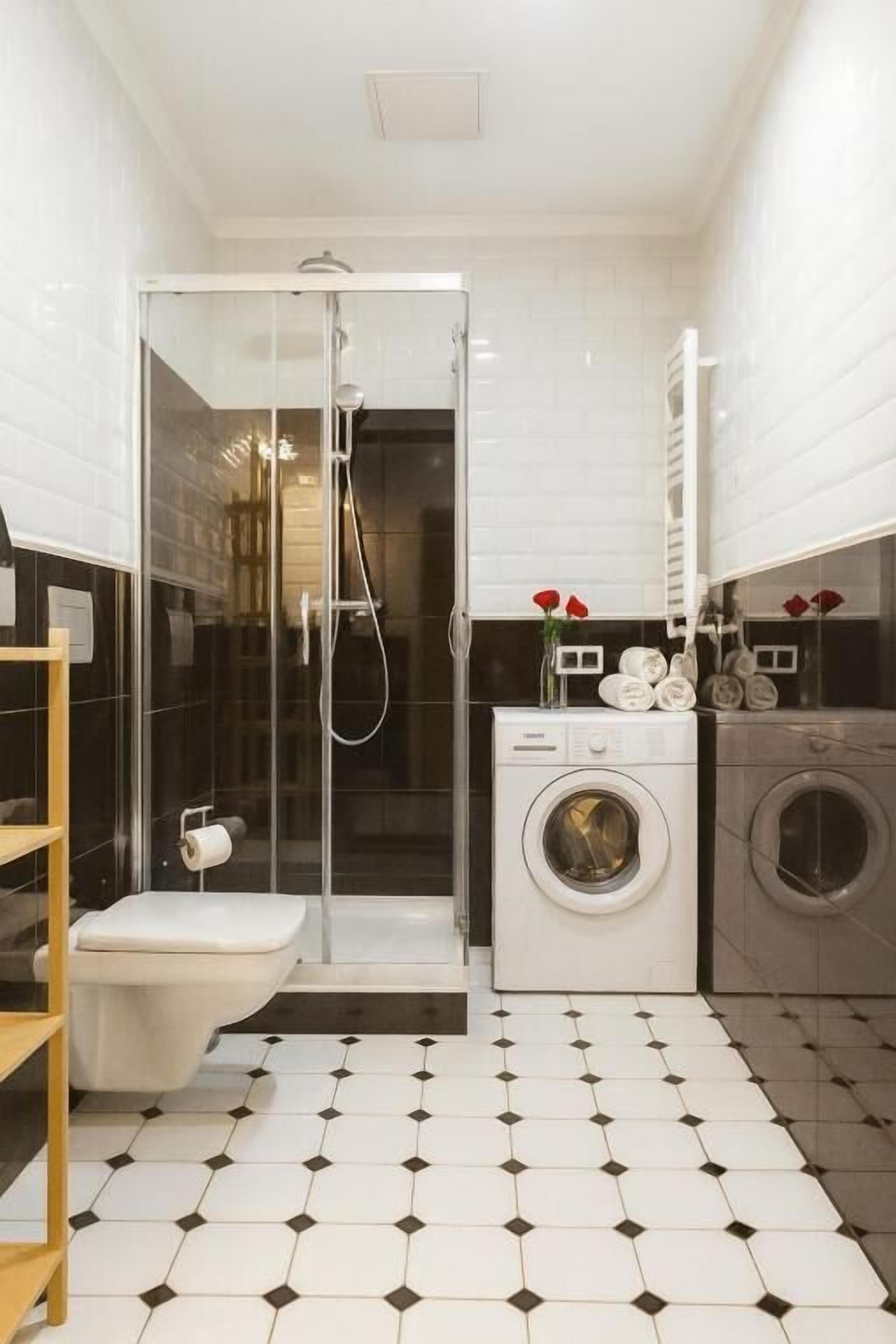 Un bagno compatto con box doccia in vetro, un water, una lavatrice e un'asciugatrice.
